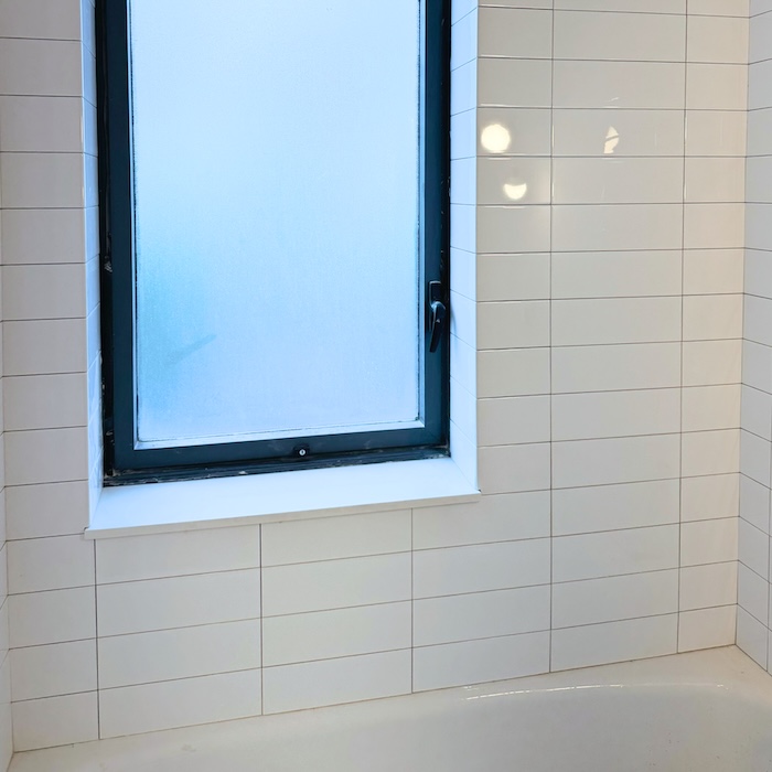 Completed bathroom tile installation in NYC with white tile and natural light